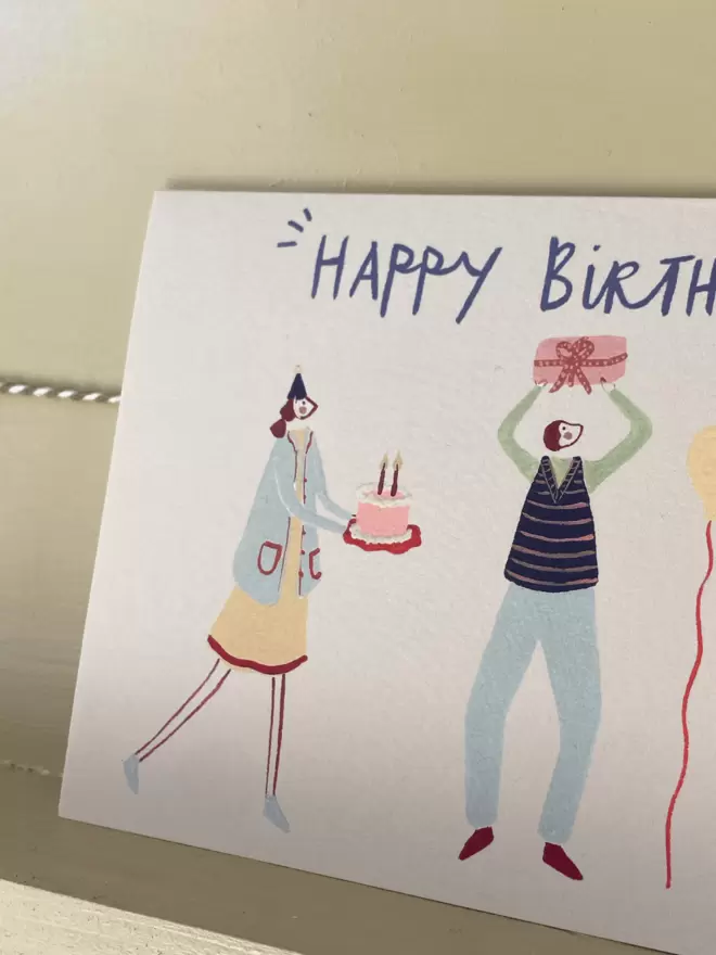 birthday card with people celebrating with cake, presents and balloons