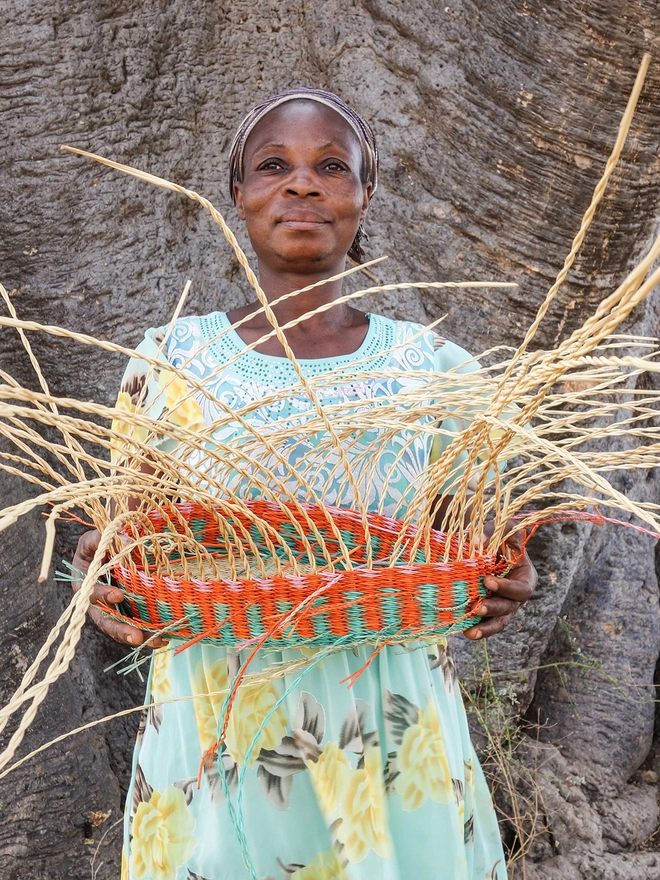 Ghanaian weaver holding part-woven basket