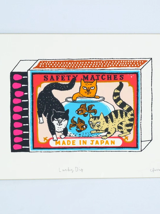 Three Cats And Two Fish Matchbox Lucky Dip, a colourful matchbox design in the centre of a white screenprint. 