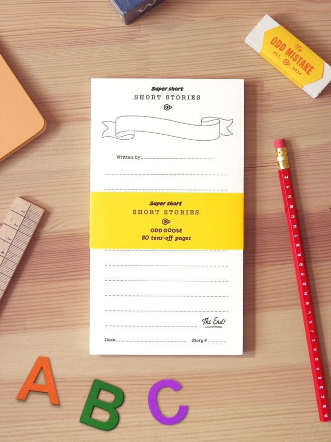 Odd Goose Super Short Stories creative writing notepad seen top down with stationery tools around it