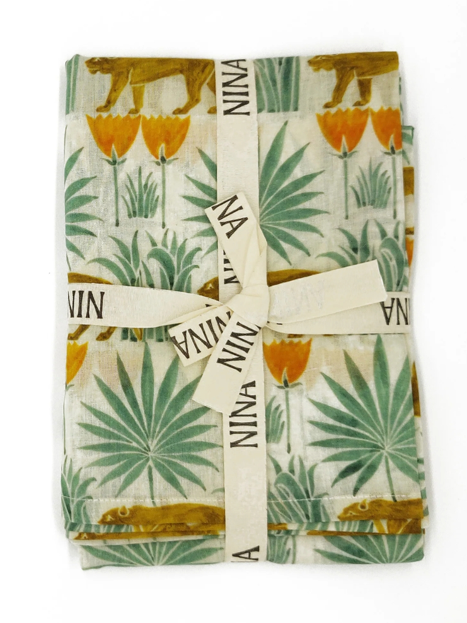 Lioness Amongst the Palms Muslin. A muslin patterned with lionesses in palm trees, folded.