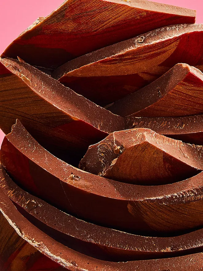 A stack of milk chocolate Easter egg pieces decorated with red and gold cocoa butter