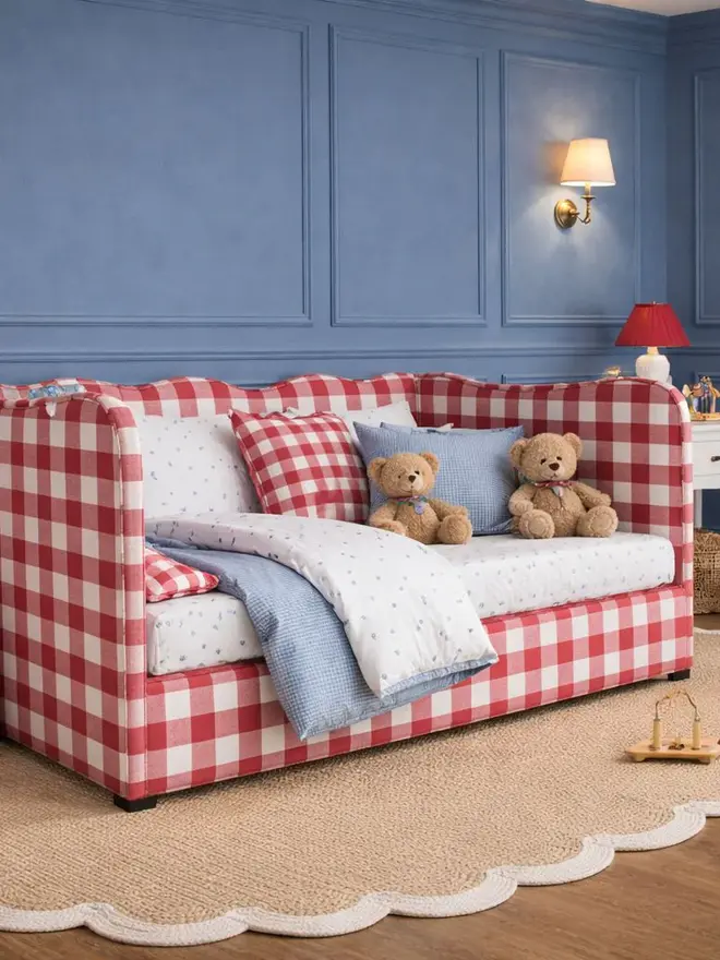 'the lochlan' red upholstered wavy children's trundle bed. a sofa-style children's bed with a wavy headboard in red gingham, with cushions and beddding.