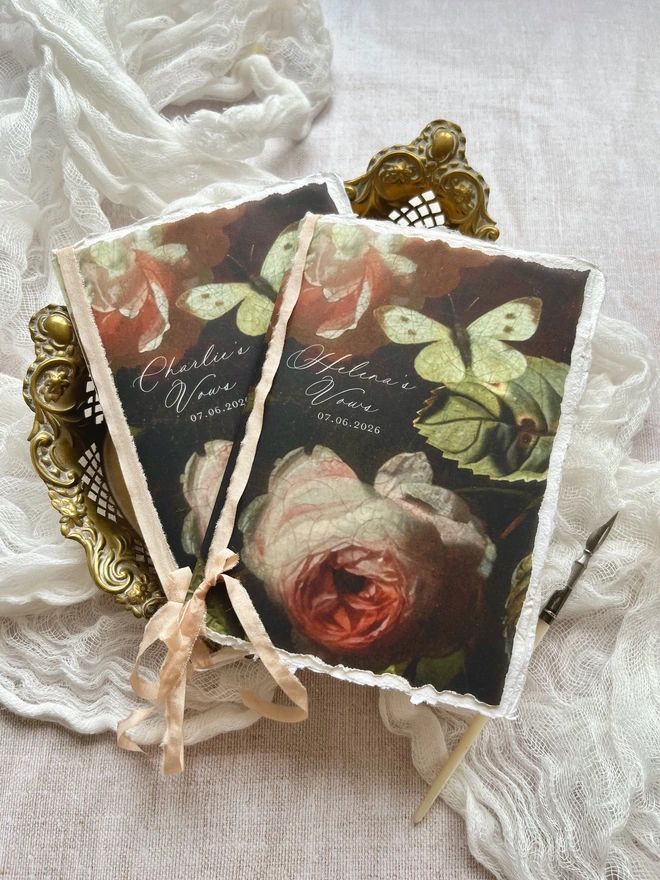 Butterfly and Roses vow booklets. 2 x A6 size tied with ribbon. Romantic floral booklets with the design printed on vellum and with 2 handmade paper inserts giving 8 sides on which to write your vows.