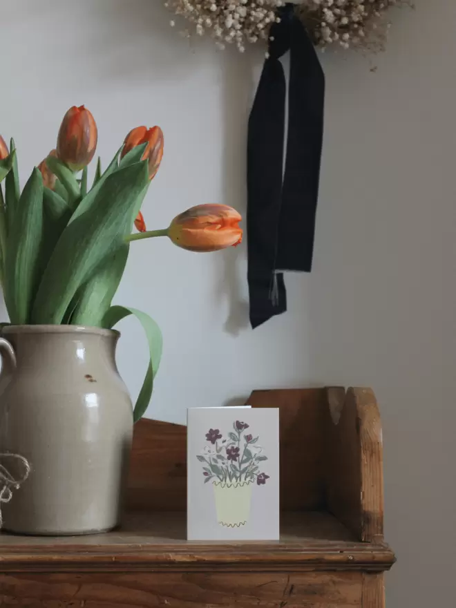 greetings card with hellebores on next to vase of tulips.