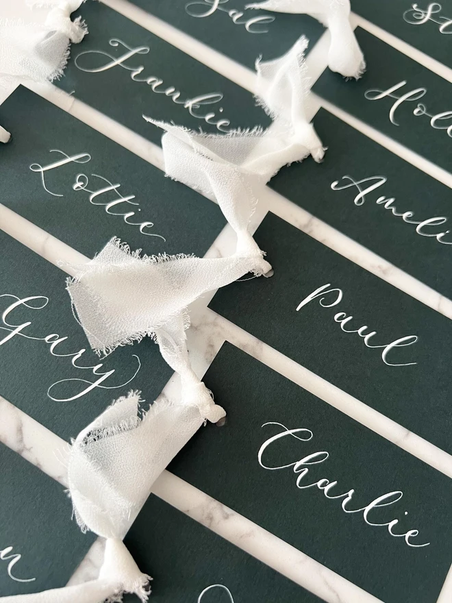 Personalised Calligraphy Wedding Forest Green Place Cards, grouped together with white ribbon. 
