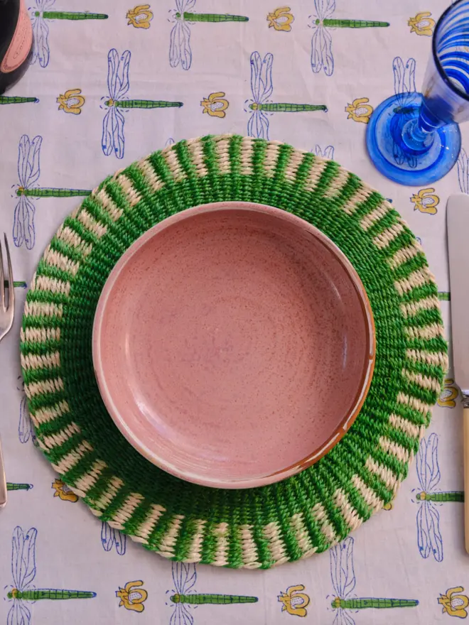 Green placemat sitting on a patterned tablecloth