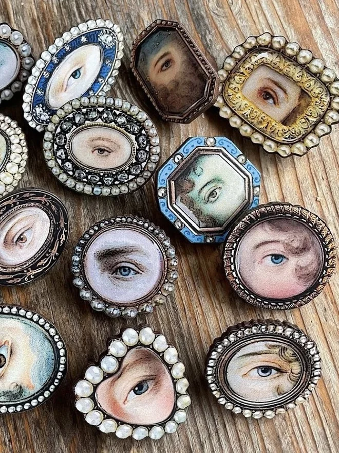 a collection of lovers eyes brooches laid on a vintage wooden surface