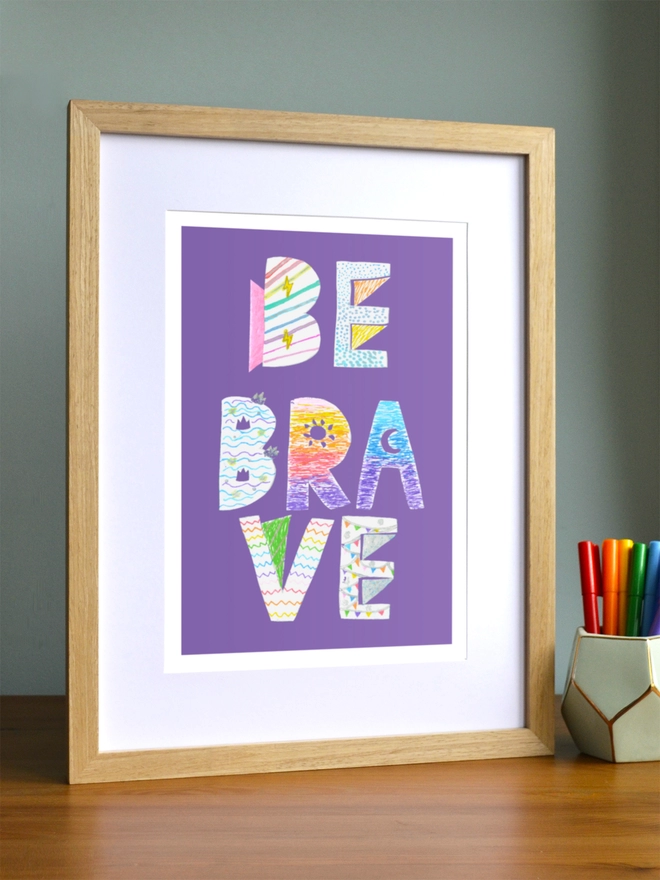 Art print saying 'Be brave' in a brown frame in a child's room