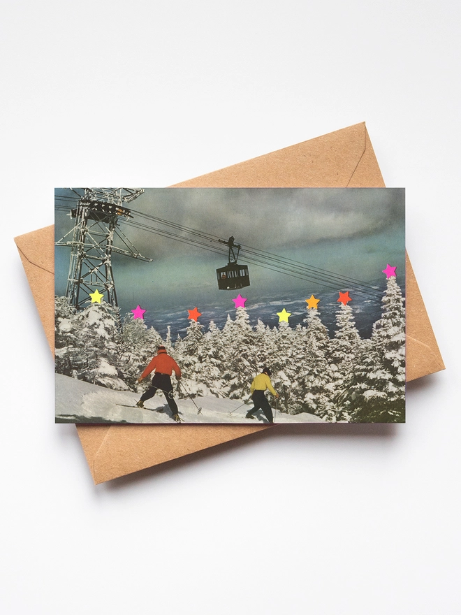 Two skiers are awkwardly sliding down a ski slope covered in snow. Thre are lots of snow covered trees with neon stars on top. 