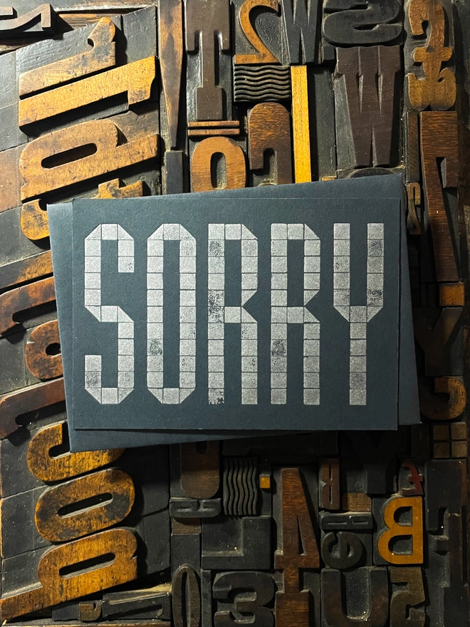 Sorry! A beautiful typographic letterpress postcard printed with metallic silver inks printed on rich thick  colourful card; ideal to send a sympathy note to a friend or loved one.