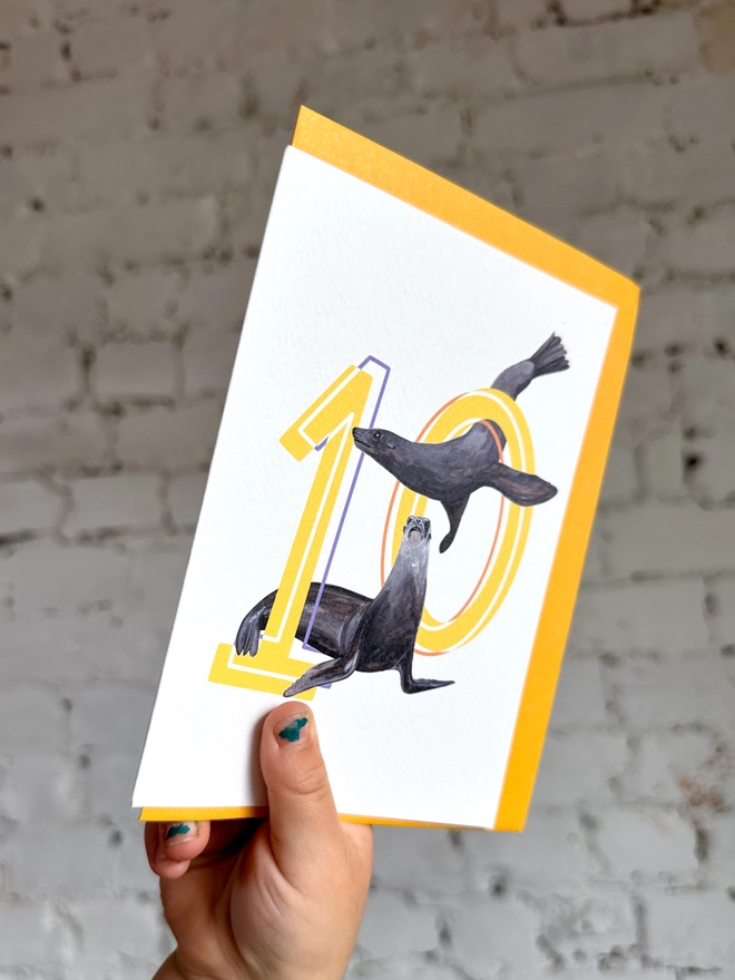 Number ten card with yellow numbers with sea lion illustrations and a yellow envelope