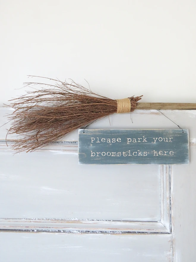 Distressed hand painted wooden sign with broomstick parking message