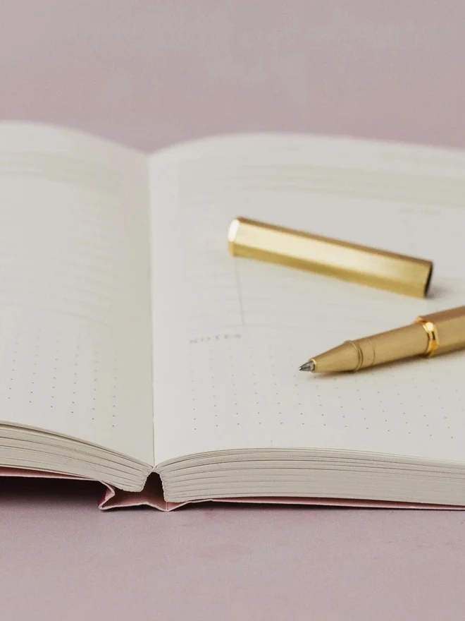 Close-up of an open Colour Study Daily Planner with a gold pen