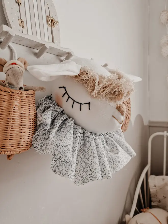 Sheep Head Wall Mount, a hanging sheep head decoration sitting against a plain wall in child's bedroom. 