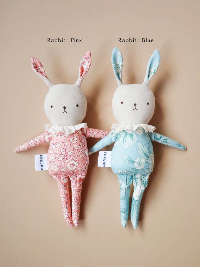 Handmade rabbit dolls with pink and blue floral-patterned fabric, off-white lace ruffle collar. A white tag with the brand name ‘BOKUNO’ is sewn on the side.
