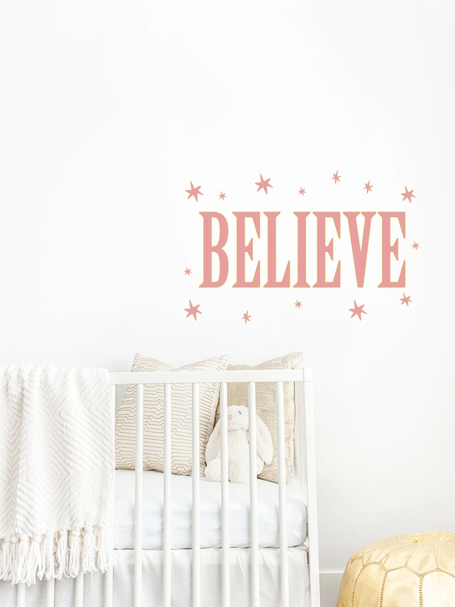 believe wall sticker with pink stars surround wording above a cot