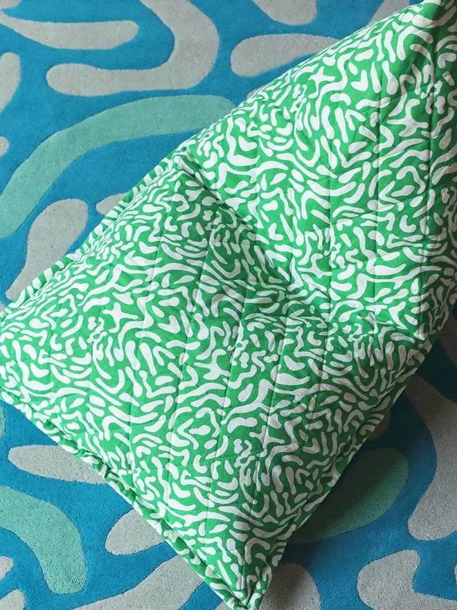 Lagoon Hand Tufted Rug, a blue rug sitting underneath a colourful bean bag. 