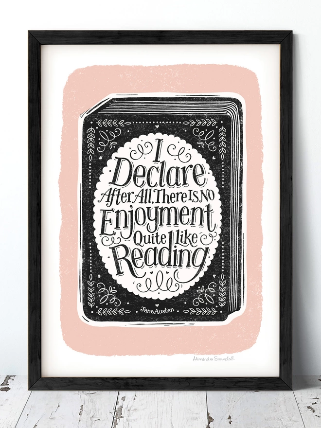 hand lettered reading quote on a black and white book with prink background in a black frame