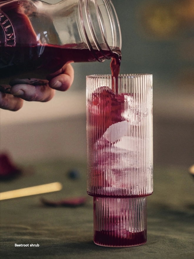 Bright purple drink being poured into long glass