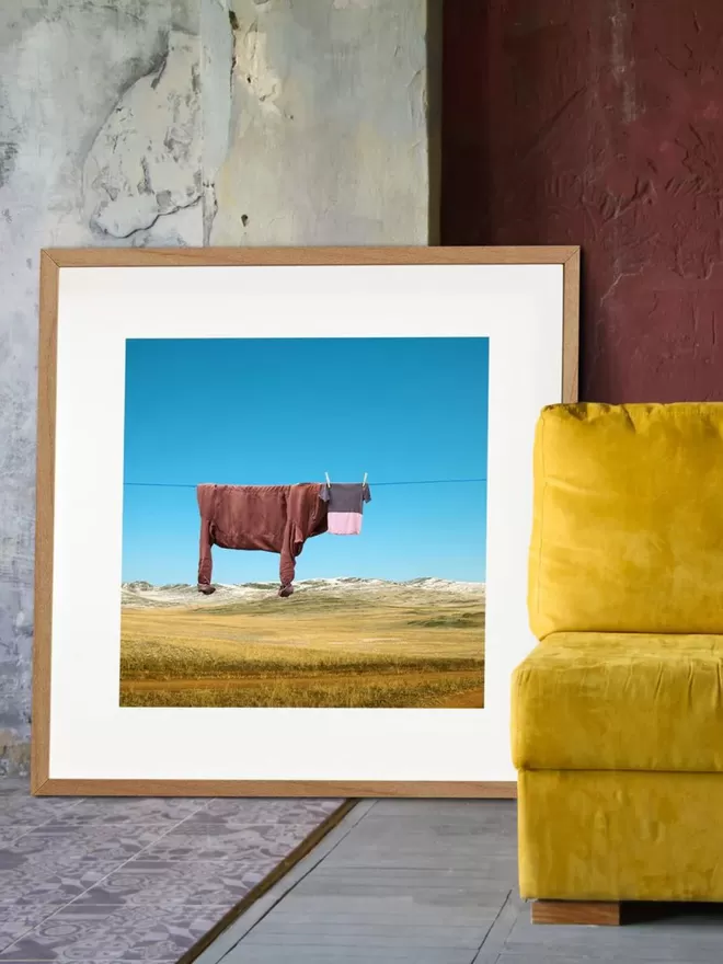 Original print of Smooothie the chocolate cow hung on clothes line in the mountains seen on the floor of a sitting room.