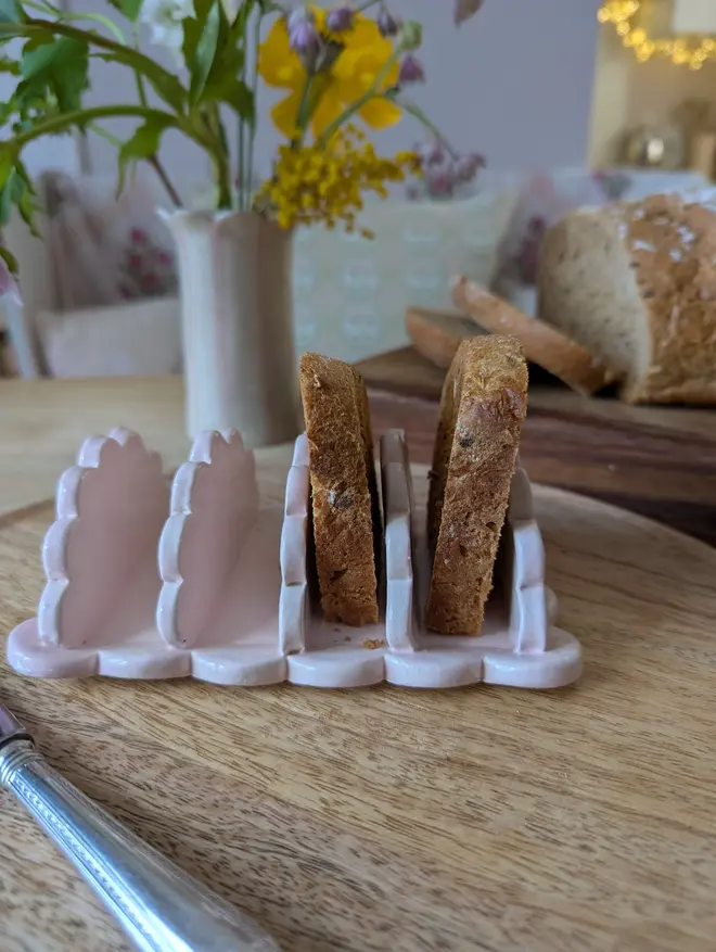 scalloped stoneware toast rack. a pink rack for toast with scalloped edges.