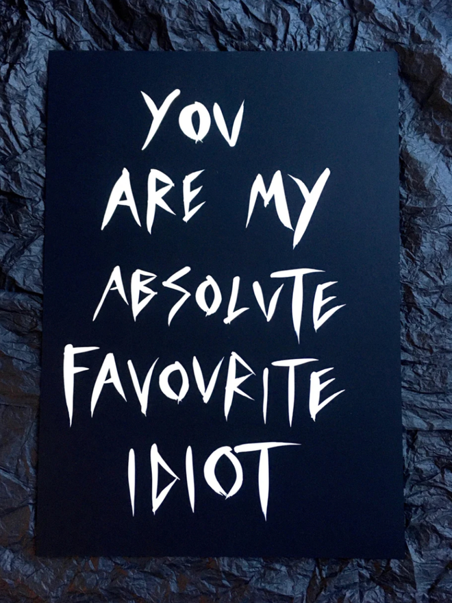 'Favourite Idiot' painting. White ink on black paper.