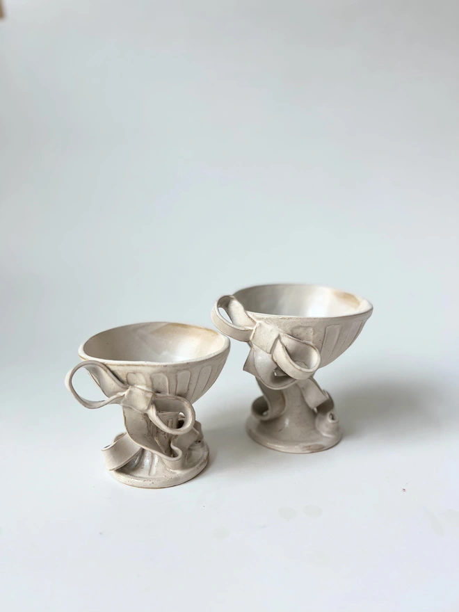 two white bowls on feet, with bows 