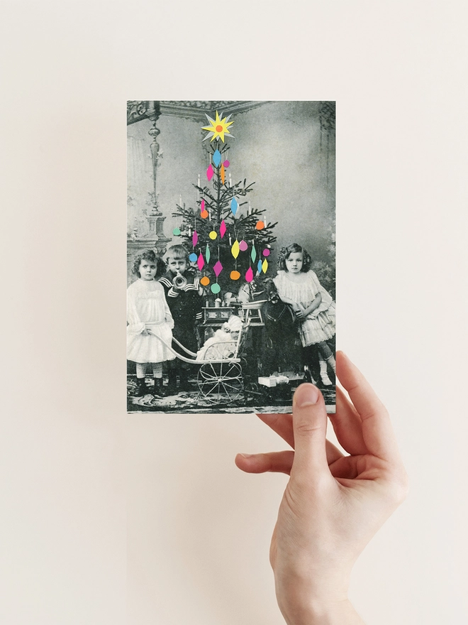 Victorian children stand next to a colourful decorated Christmas tree with their newly opened presents.