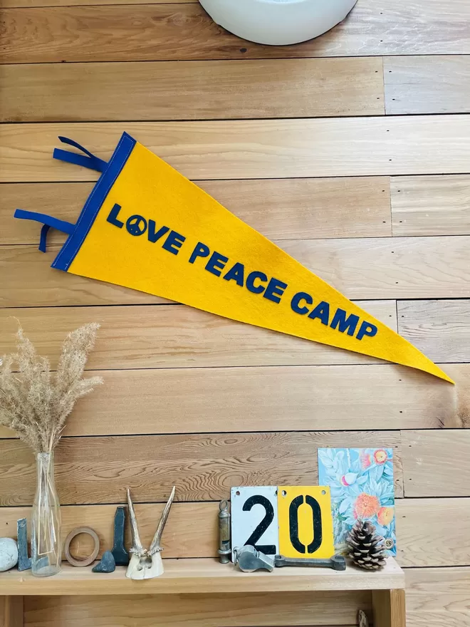 Love peace camp pennant flag hanging on a wooden wall.