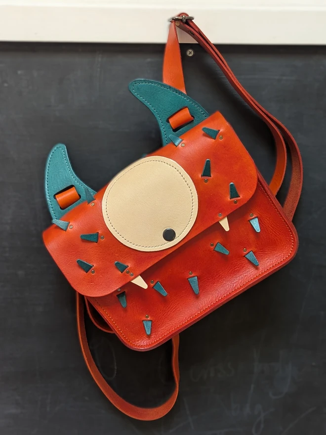 Leather monster backpack in orange and blue front view.