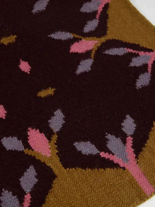 Hedgerow Flatweave Rug, a colourful rug sitting on a plain backdrop. 