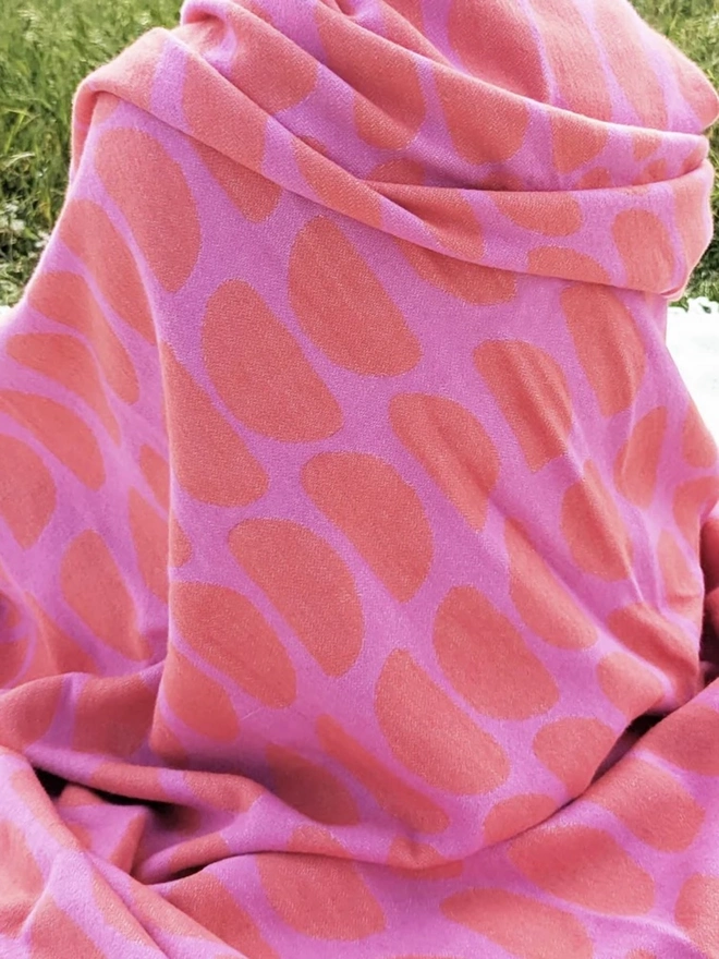 Organic Cotton Throw, a woman sitting with a throw draped on her outside. 