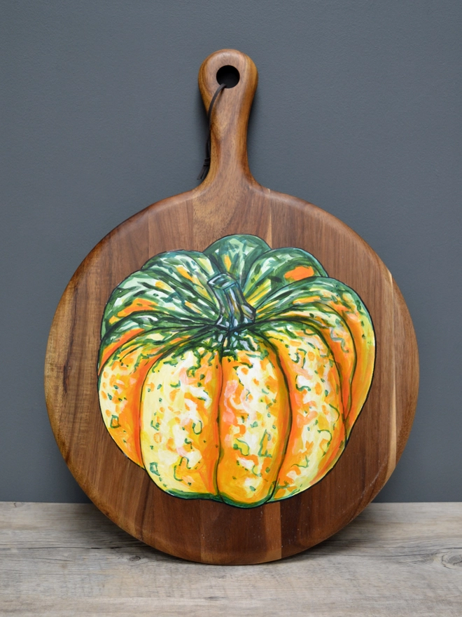 Wooden serving board with a handpainted design of a carnival squash