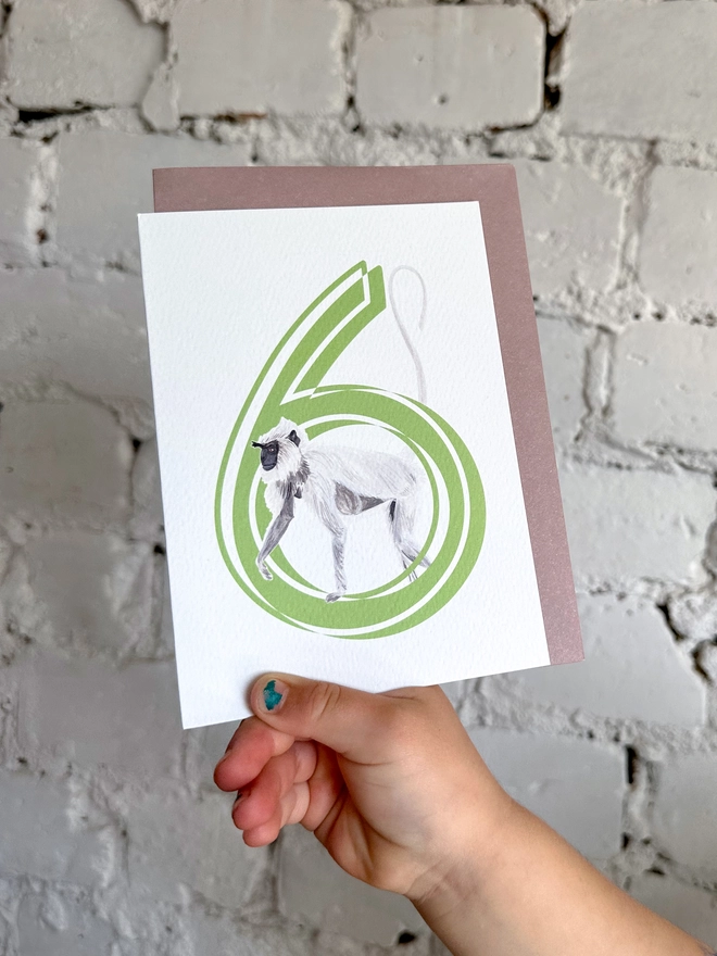 white card with a big green number 6 and an illustrated monkey with a purple envelope