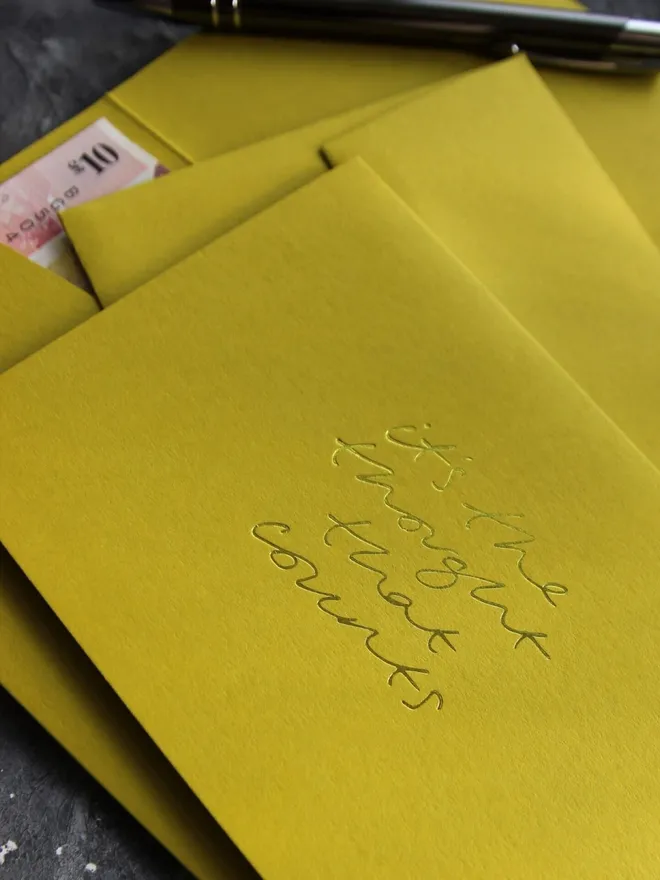 Hand foiled cash card or money wallet in a chartreuse green colour handfoiled in shiny yellow foil text which says ‘It’s the thought that counts’.