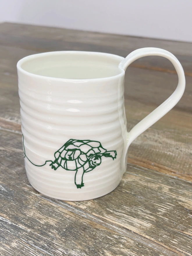 hand thrown porcelain mug with a continuous line design of a tortoise on the front