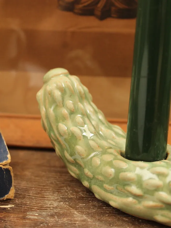 Pickle Candle Holder, a pickle candle holder sitting on a wooden surface with a candle in it. 