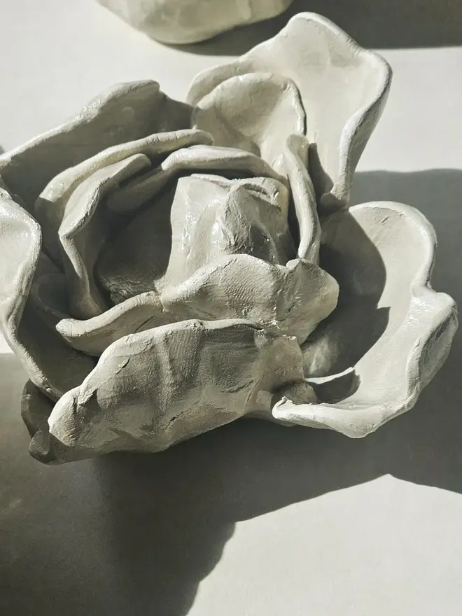 hand-sculpted ceramic flower in a gray mist glaze, featuring individually crafted petals and natural texture. Each unique piece is wall-mountable with a carved keyhole on the back