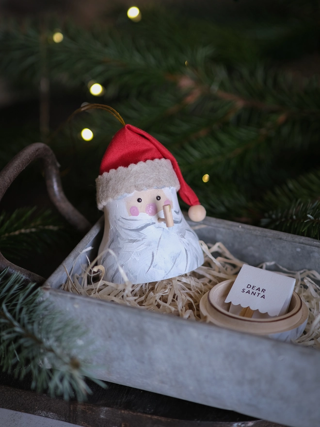 Handmade rustic Santa Christmas ornament with a white beard, rosy cheeks and red hat, with a tiny note to santa inside