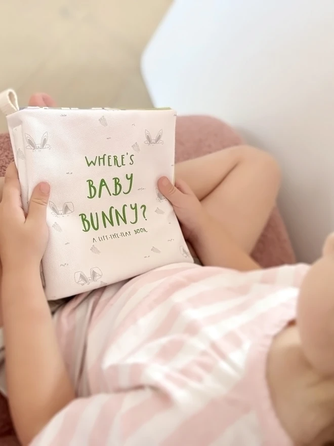 Girl holding a closed Where's Baby Bunny? Lift-the-flap Cotton Soft Book