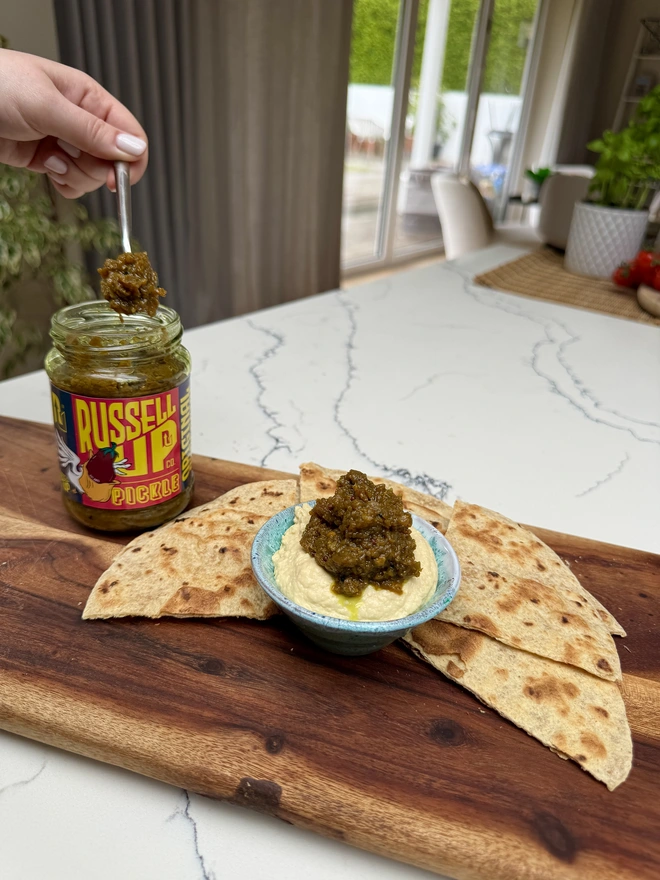 father's day pickles - cheese set. a jar of aubergine pickle being spooned onto pita bread.