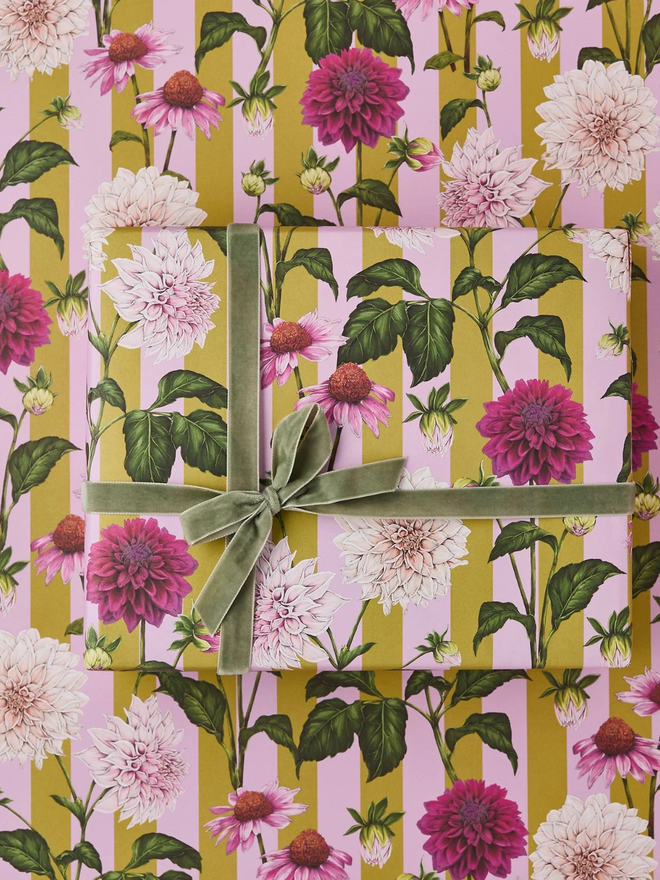 floral riot gift wrap sheet. a box wrapped in pink illustrated floral gift wrap with a green ribbon.