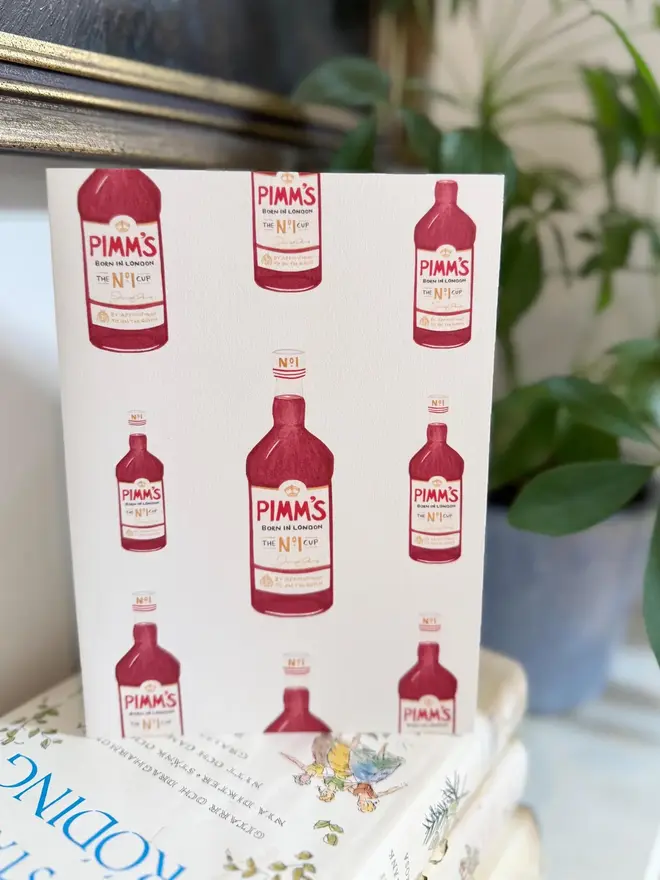 pimms bottle illustrated card. card placed on top of book pile.