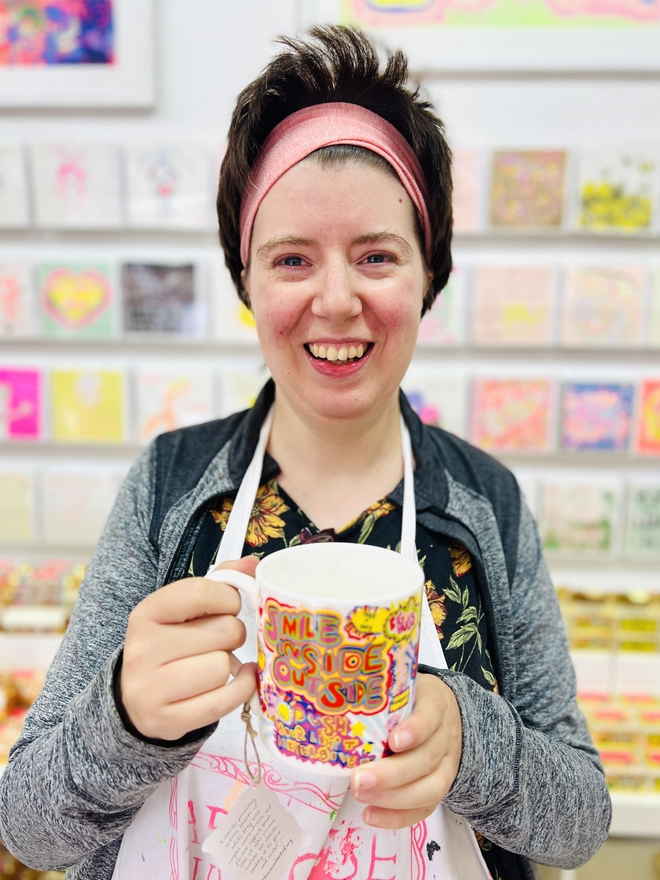 Happy artist holding full of joy charity fine bone china gift mug with colourful positive messages