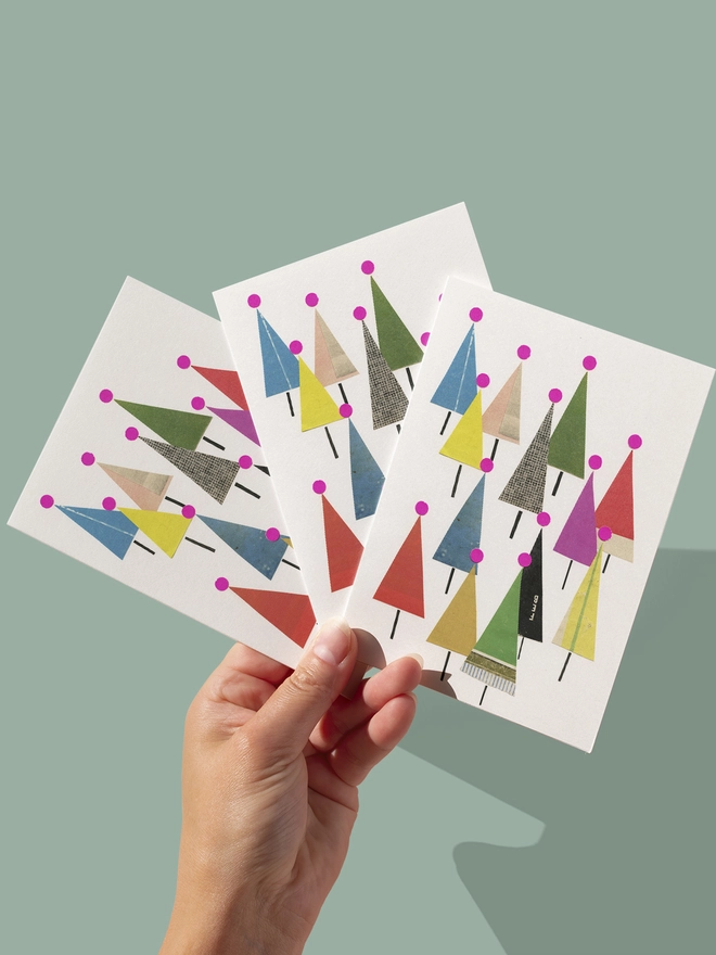 A bright Christmas card depicting a forest of colourful fir trees.