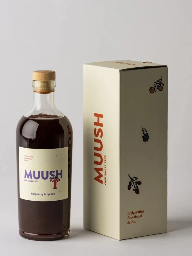 Raspberry & Lychee Elixir, bottle of soft drink on a plain surface accompanied by a packaged bottle. 