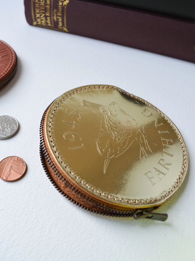 an open gold leather coin purse with a metal zip and loose change
