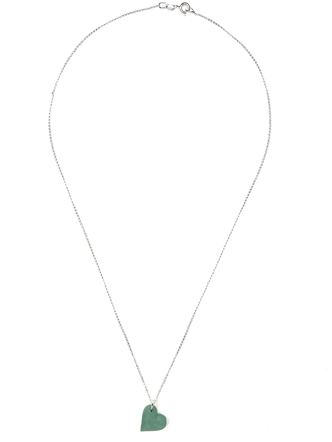 Recycled fishing net heart of a silver chain, necklace , laid out flat on a white background 