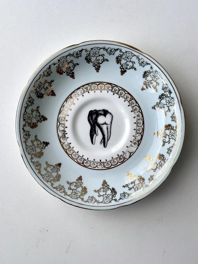 vintage plate with ornate border has a black and white image of a victorian molar tooth in the centre